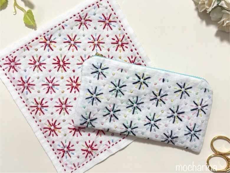 刺し子の紺色の花火模様のポーチと刺し子ふきんの赤い「花火」の写真。ふきんの上にポーチを少し重ねておいている様子。