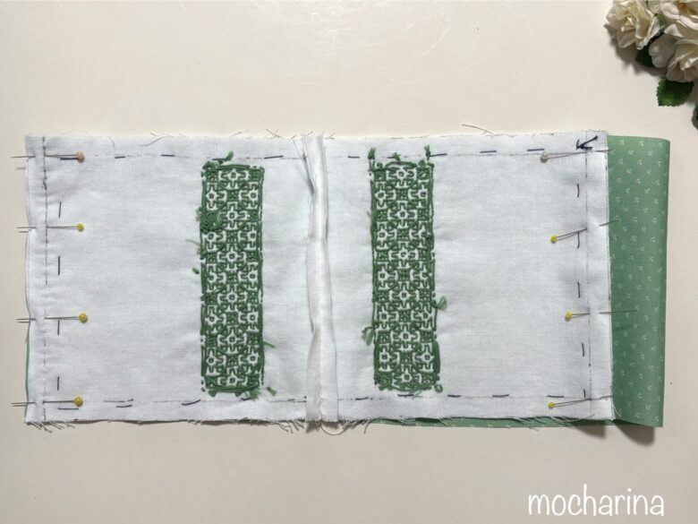 巾着袋の作成途中の写真。表地と裏地を中表に合わせ、まち針をとめた様子。