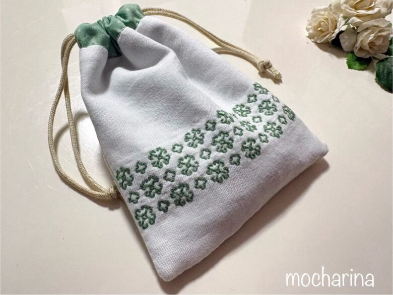 マーガレット模様の刺し子巾着袋の完成写真。緑色の刺し子マーガレットが3段並んだデザイン。巾着を絞った様子。