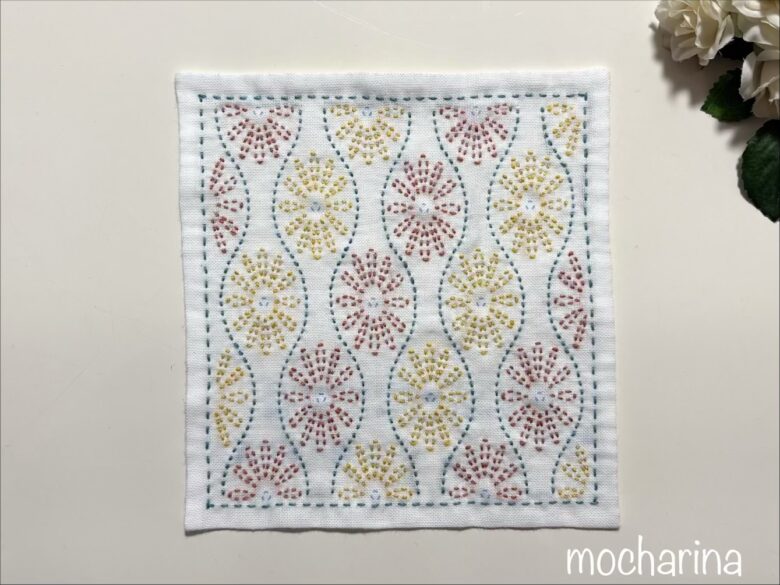 波模様の間にある花模様を縫った写真。オレンジと黄色の糸で花模様を縫った様子。