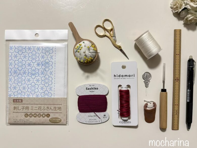 刺し子に必要な材料の写真。刺し子キット・刺し子糸・針・指ぬき・糸通し・定規・ペンなどを並べた様子。