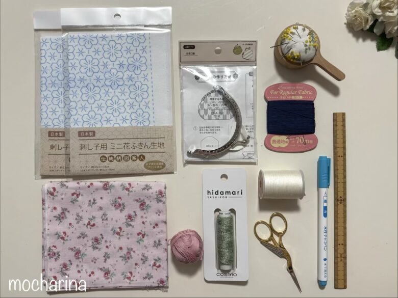 刺し子がま口の材料の写真。刺し子キット、刺し子糸、がま口金、布、裁縫道具が並んでいる様子。