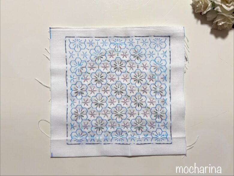 がま口型に刺し子をした途中写真。ピンクと緑色で縫った様子。