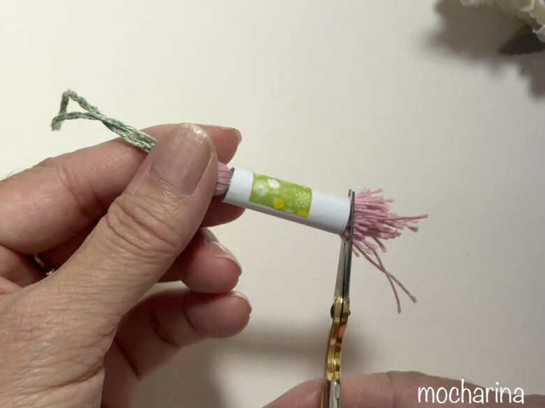タッセルの糸束を切り揃える写真。巻き付けた紙をガイドに、糸束を切りそろえる様子。