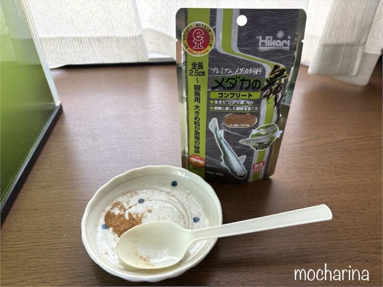 「メダカの舞」コンプリートの写真。エサ袋の前のお皿には、細かく砕いたエサを乗っている様子。