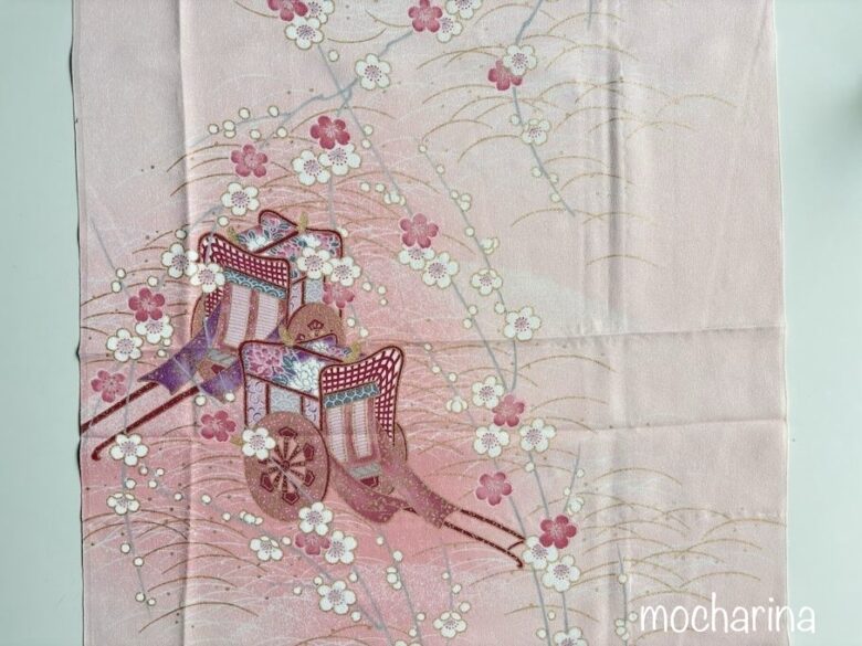 御所車が描かれたピンク色の正絹の写真。御所車と梅が描かれた美しいデザイン。