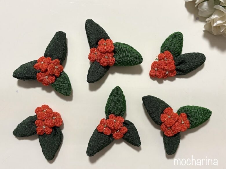 ちりめんで作った金木犀6個の写真。緑色の葉っぱ3枚にオレンジ色の花3個がついたデザイン。