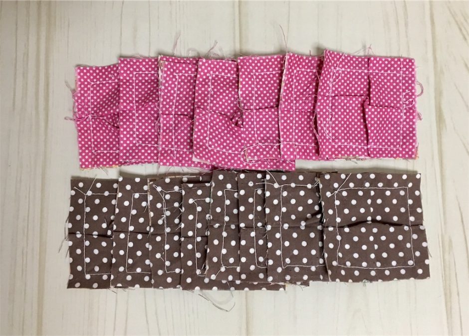 パッチワークのパフキルトのパーツを作った写真。ピンクと茶色の四角い布にタックを入れた様子。